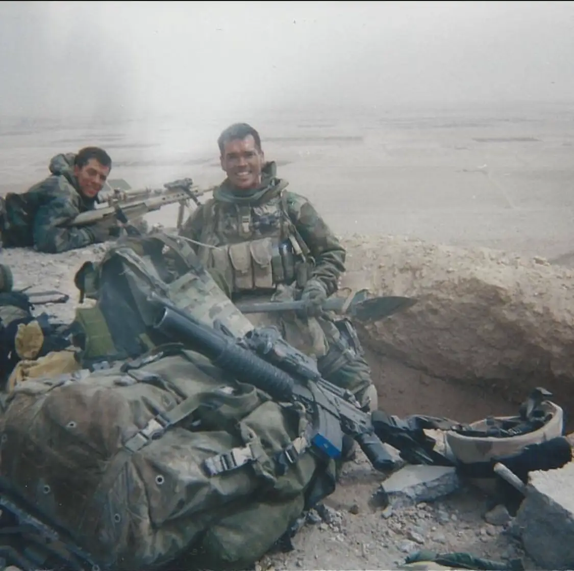 Soldiers in desert terrain with gear.