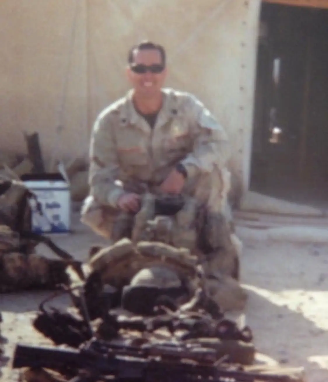 Soldier posing outdoors in desert camouflage uniform.