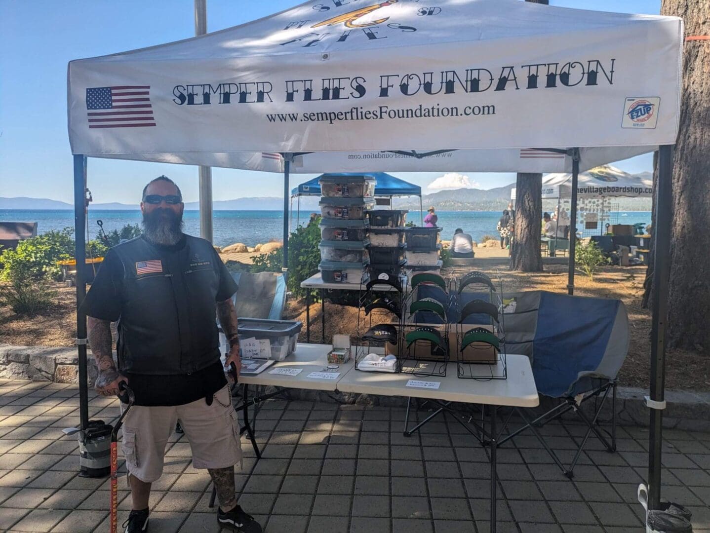 Man standing by charity booth at beach.
