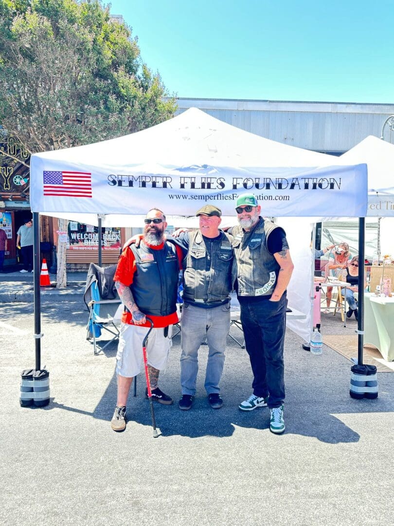 Bikers smiling under Semper Flies Foundation tent