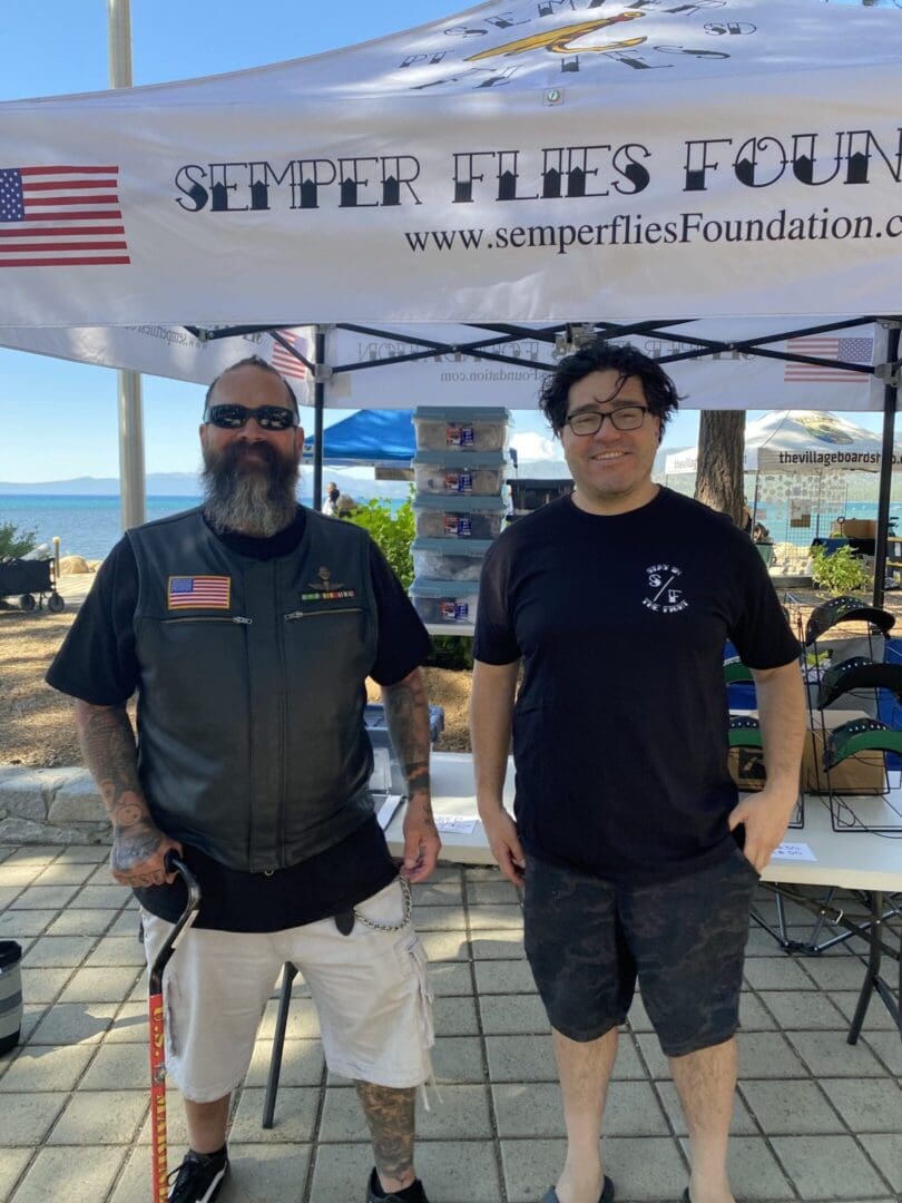 Two men standing under a foundation tent.