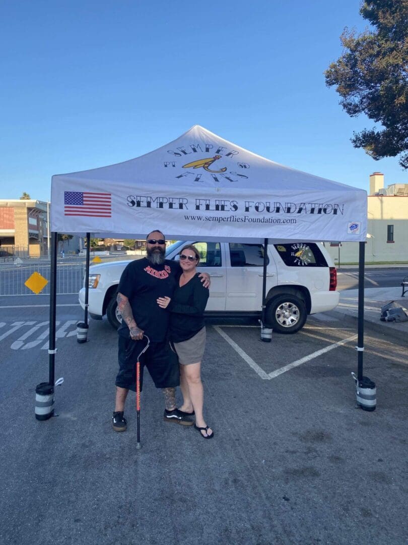 Man and woman under outdoor event tent.
