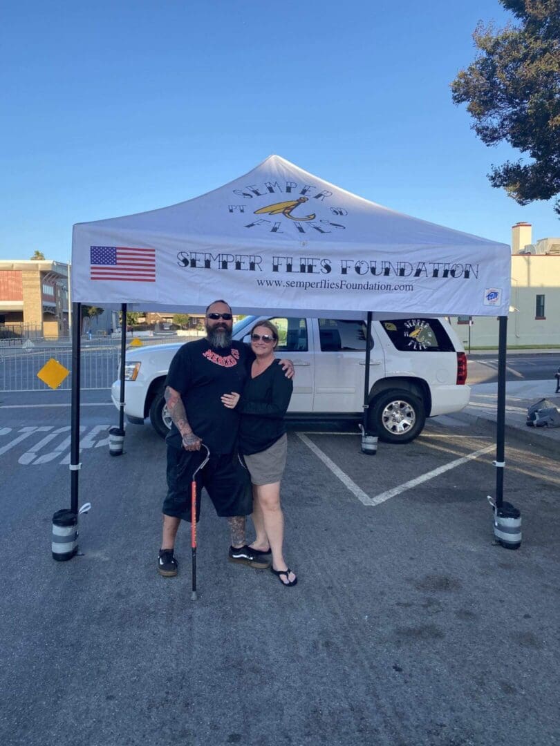 Couple standing under Semper Fi Foundation tent.