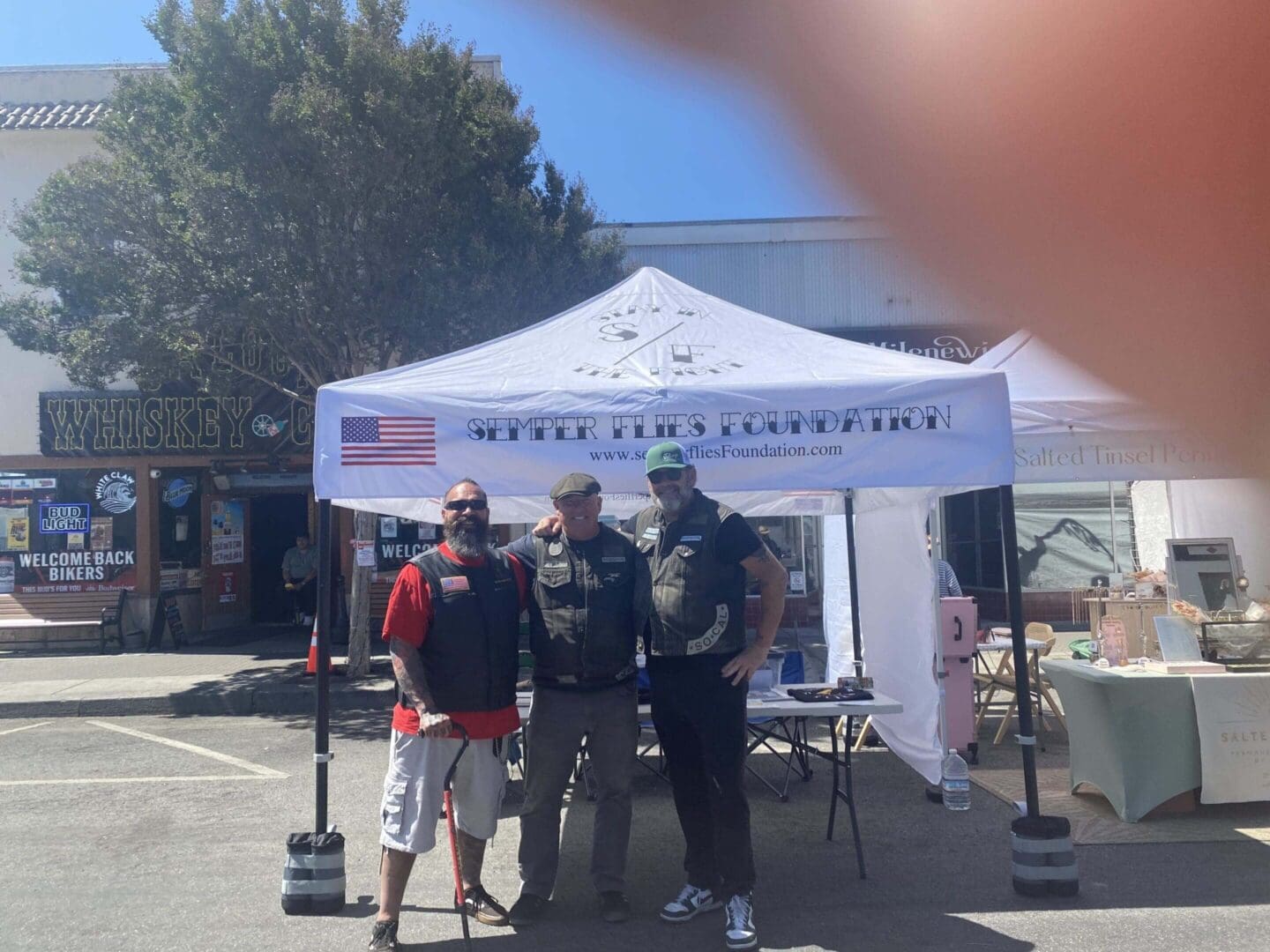 Three men standing under a tent.