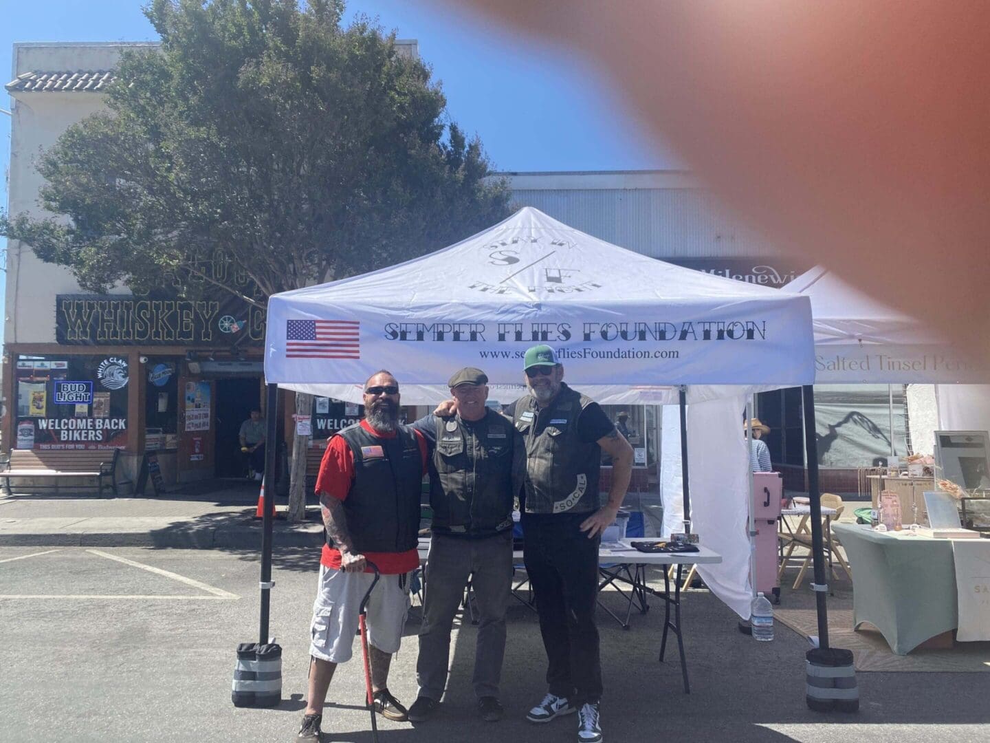 Three men posing beneath a Semper Flies tent