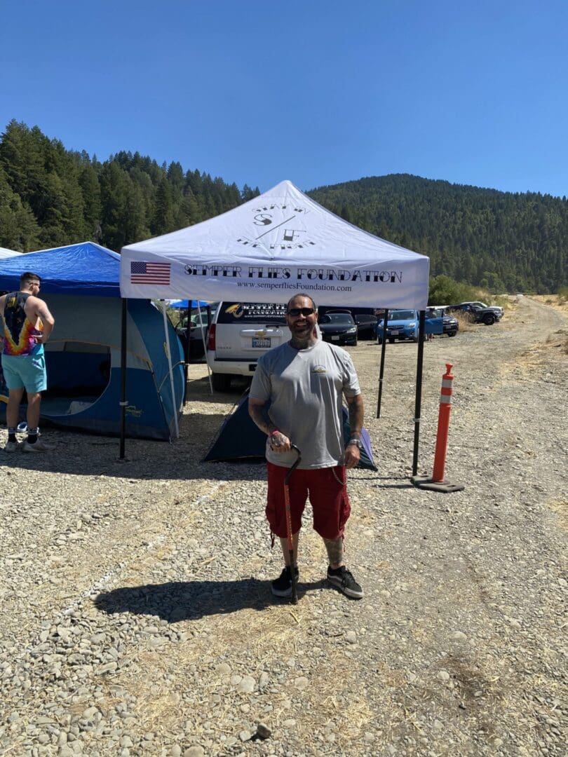 Man standing by tents in outdoor setting.