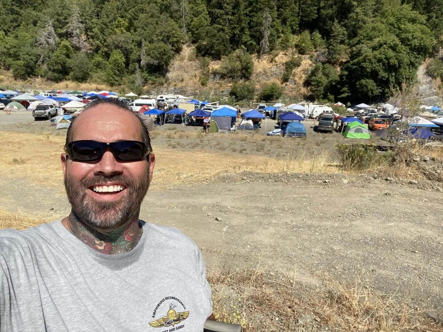 Man smiling at outdoor camping site.