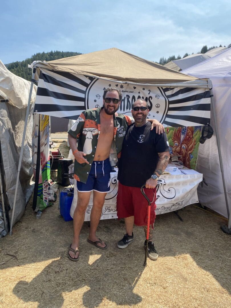 Two men smiling outside event tent.