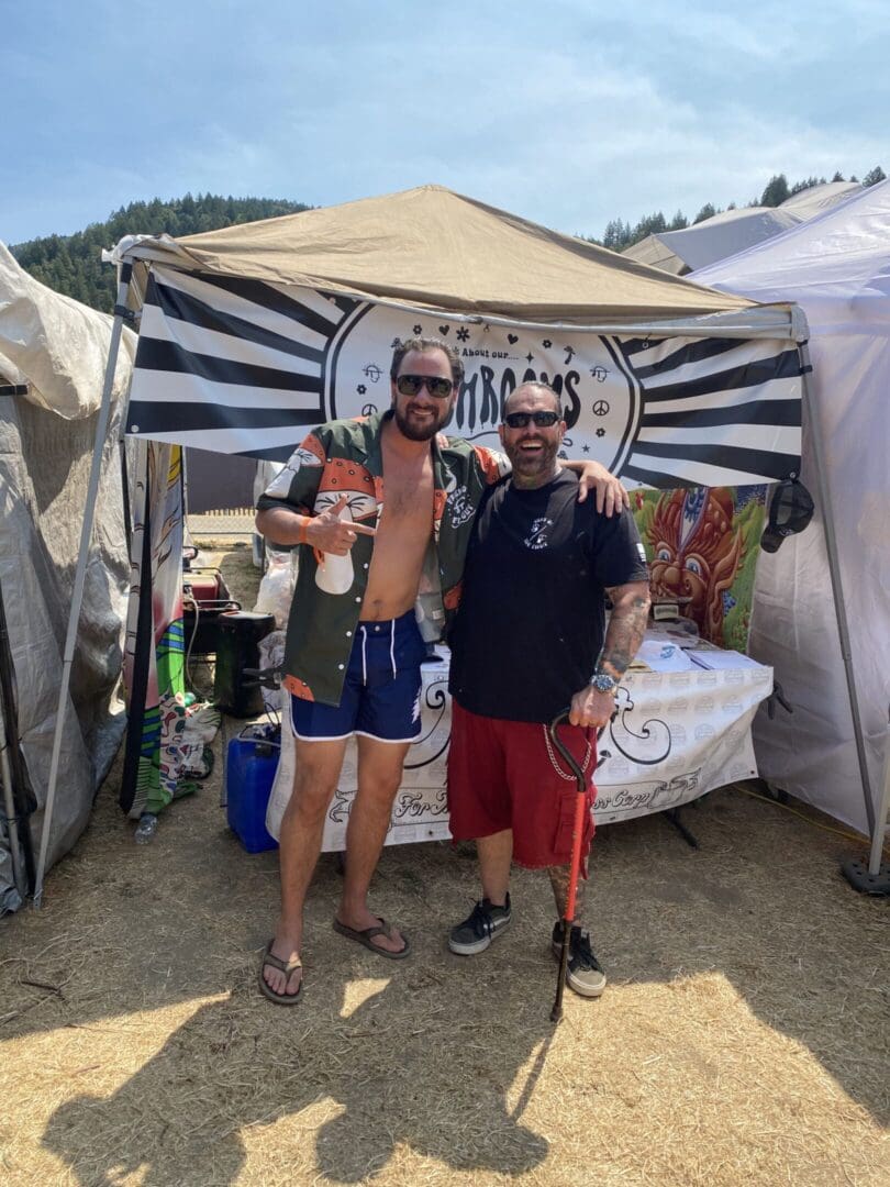 Two men posing at outdoor booth.