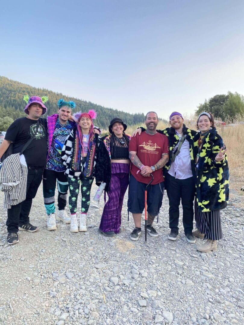 Group in colorful outfits outdoors, smiling together.