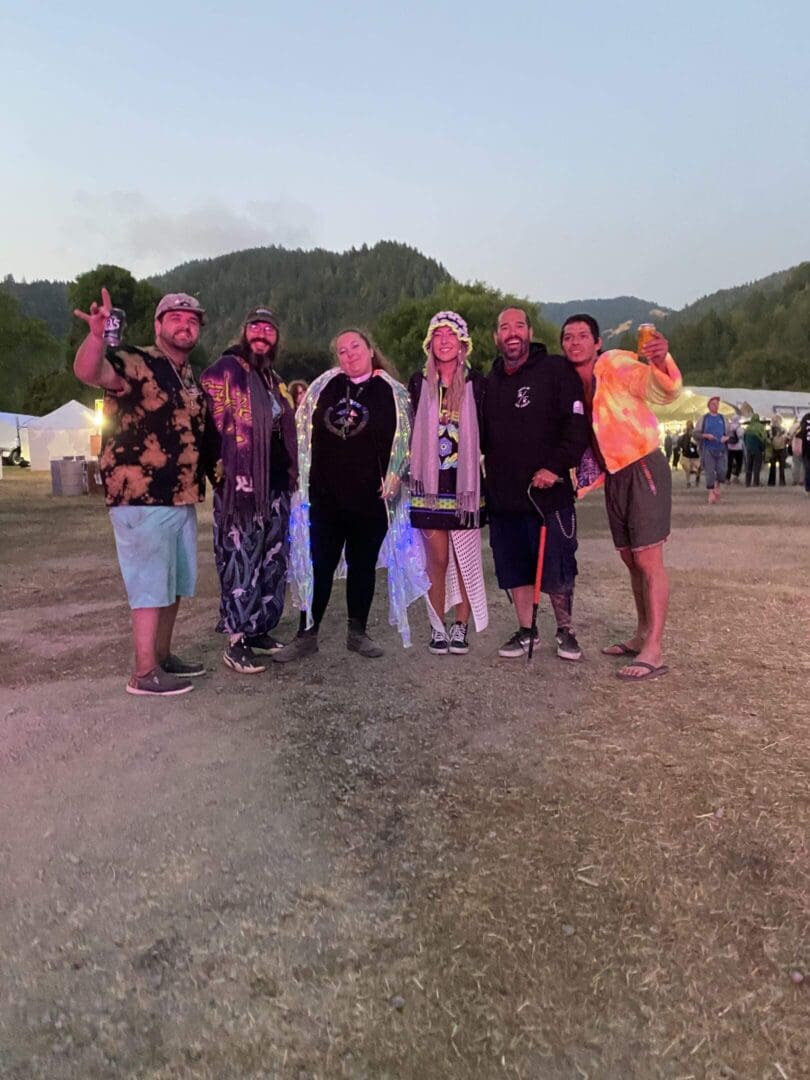 Festival-goers in lighted cloaks on grassy field