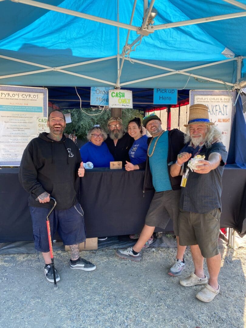 Group posing happily under a blue tent.